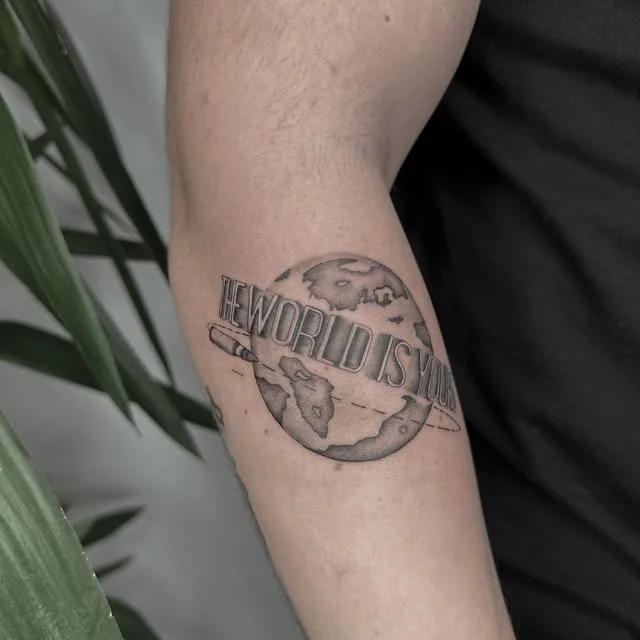 Baran'ın dünya küresi ve The World Is Yours yazılı kol dövmesi